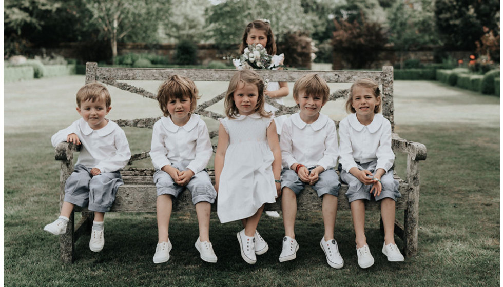 Harriet's bridesmaids and page boys posing on a bench.
