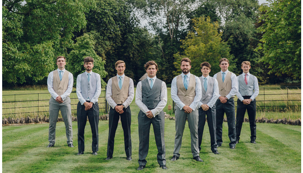 The groom and his groomsmen, all wearing coloured waistcoats posing in a formation.