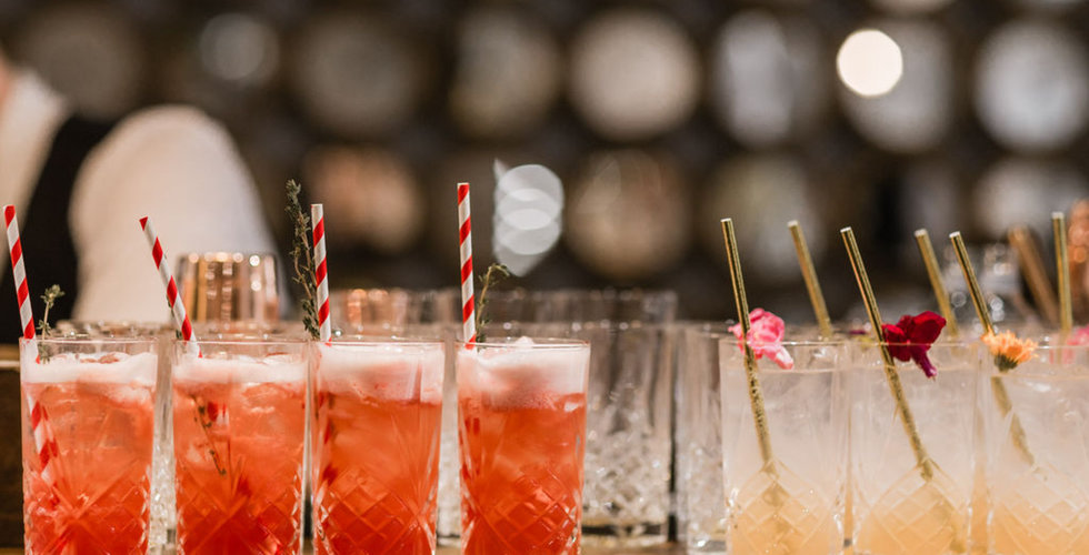 A line of cut glass highball tumblers with two different types of fruity cocktails on the bar at The Wedding Present Company showroom.