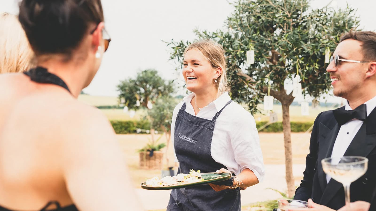 Wedding catering staff from Doggart & Squash serves canapes to wedding guests