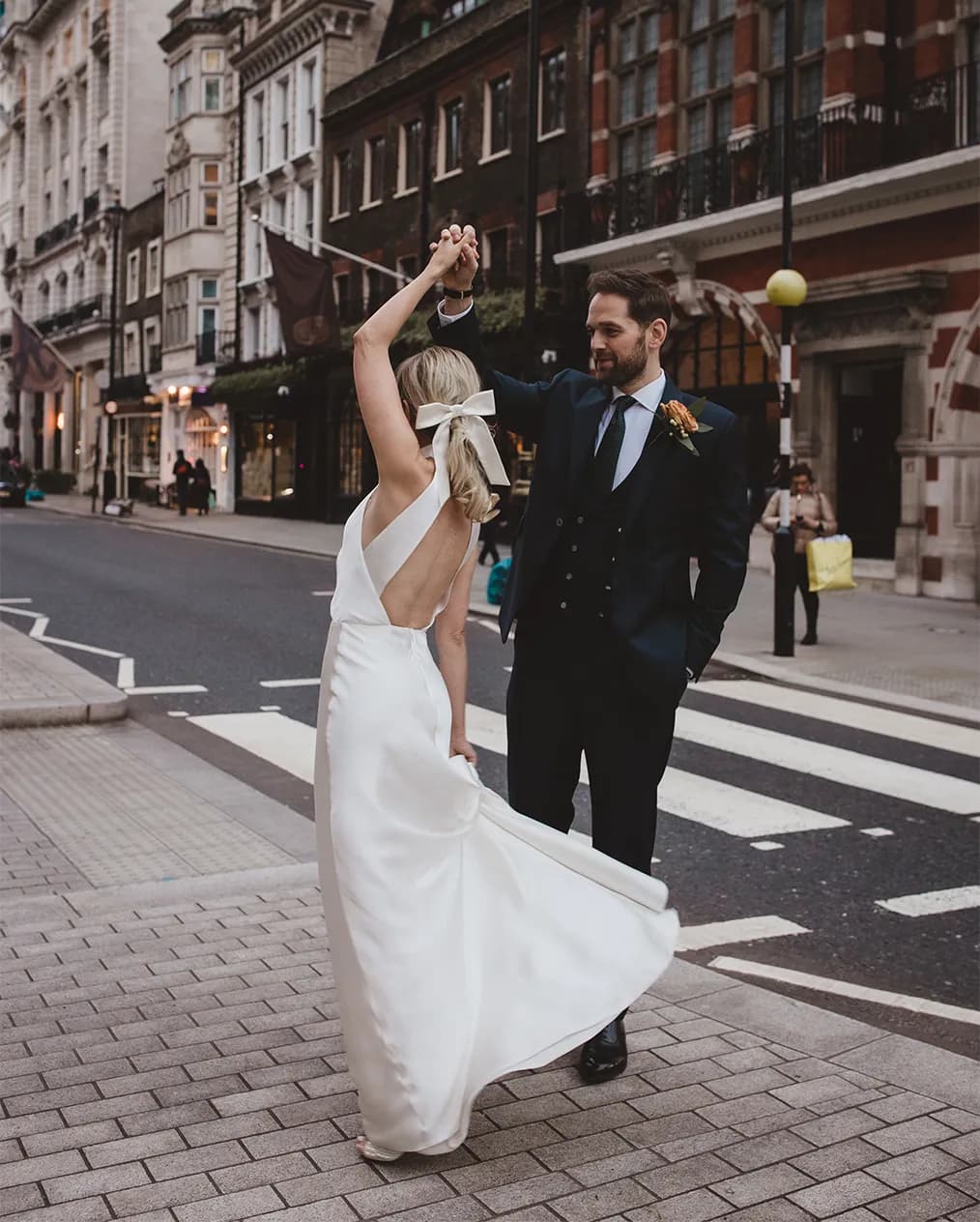 Groom twirling bride in Marylebone street by a zebra crossing