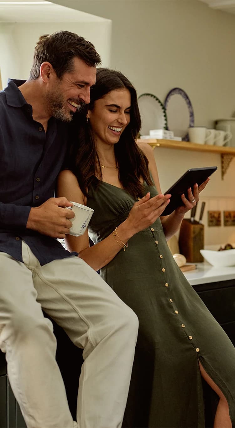 Engaged couple creates their wedding gift registry on iPad in kitchen