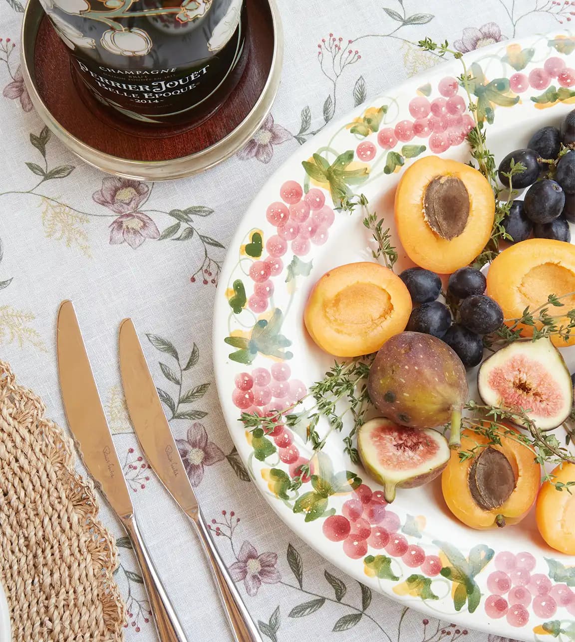 Summer tablescape on floral tablecloth features food served on Isabella Foulger's wedding present, a hand painted platter