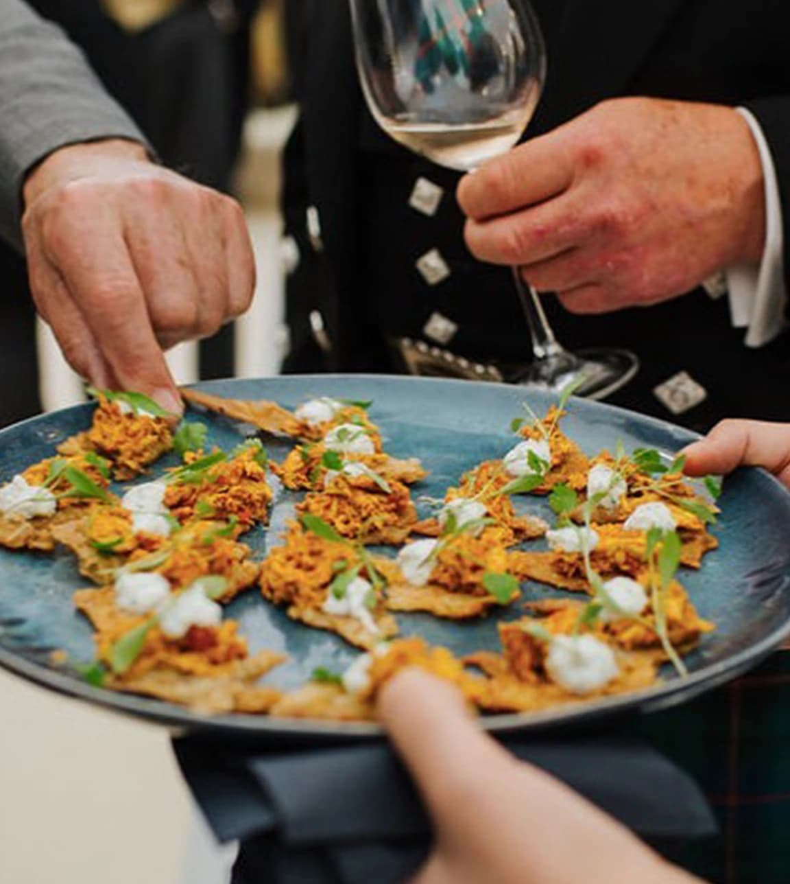 Wedding guests take evening snacks from ceramic platter.