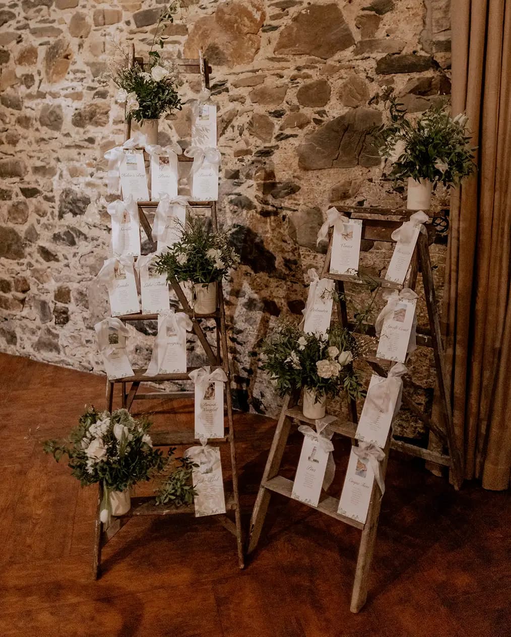 A wooden ladder decorated with foliage acts as a seating plan 