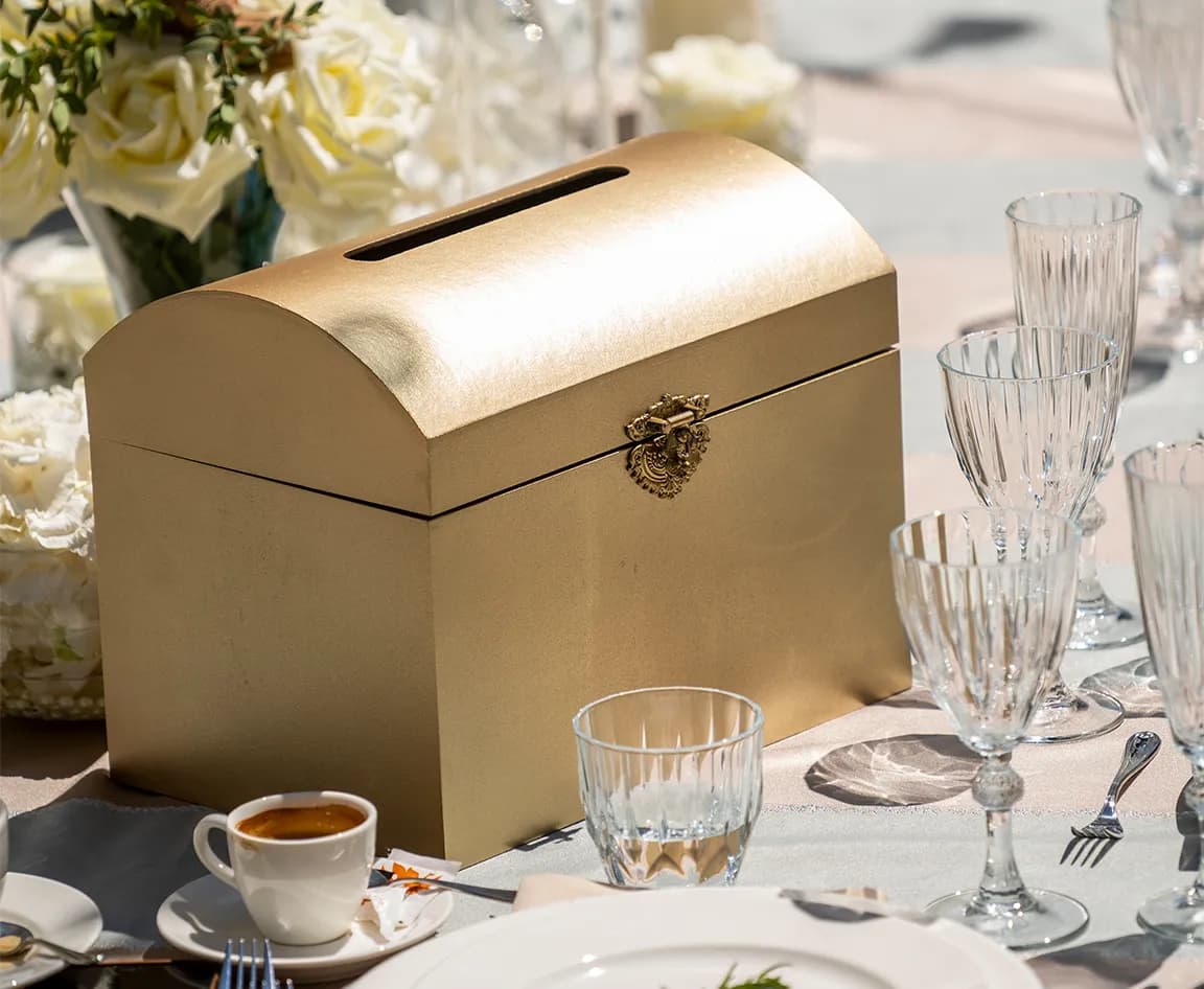 Gold charity box is placed next to a luxury wedding table décor arrangement