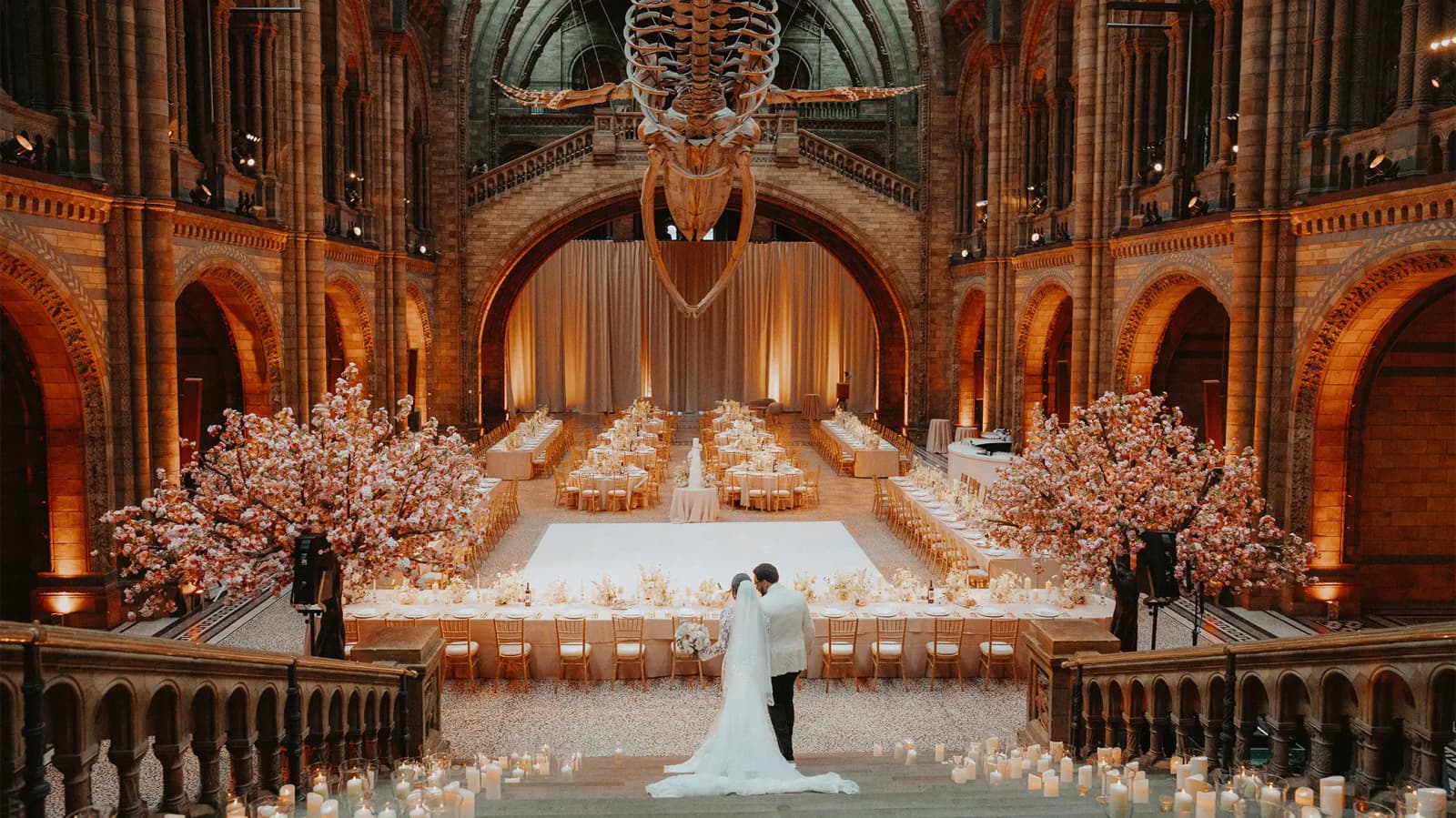 Bride and groom walking down the staircase to their wedding reception at Natural History Museum in Lonon