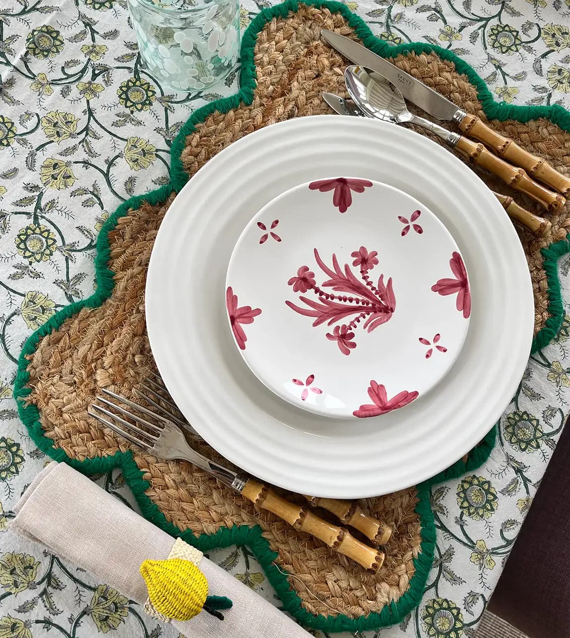 Colourful dinner tablescape styled by Georgia Hearn, featuring wedding presents including handpainted plates and cutlery on a patterned tablecloth.