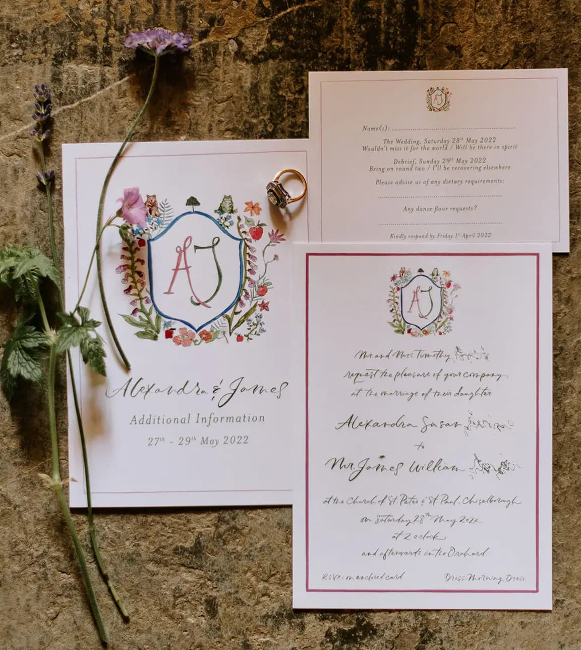 A handwritten and illustrated wedding invite is placed next to wedding RSVP and save the date stationery