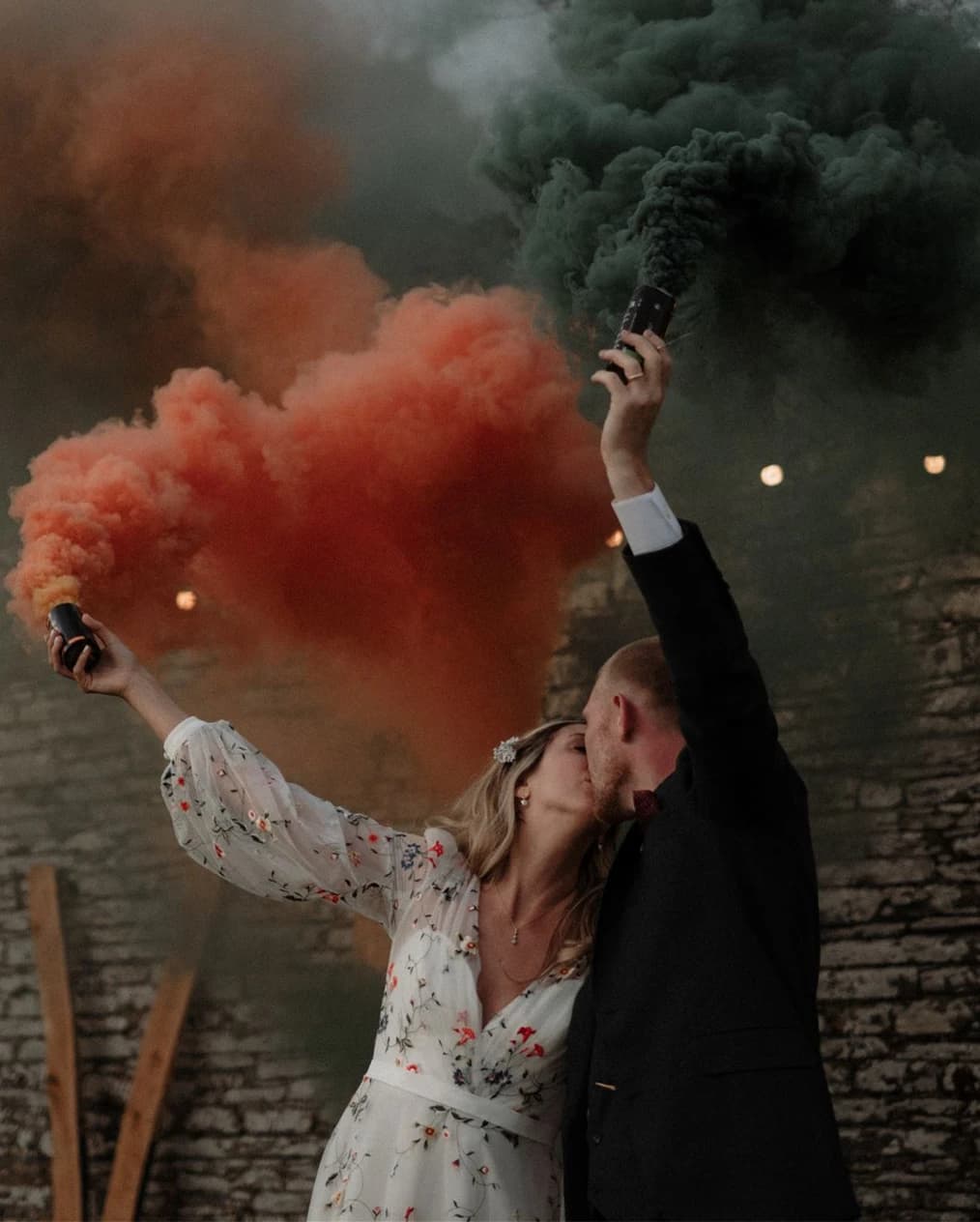 Married couple kissing while setting off colourful flares at their festival-themed Cornwall wedding