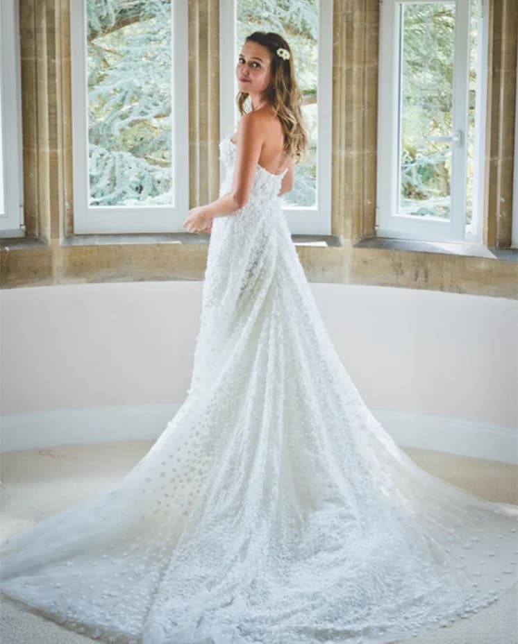 Daisy Jenks stands in the room wearing strapless dress with flower applique