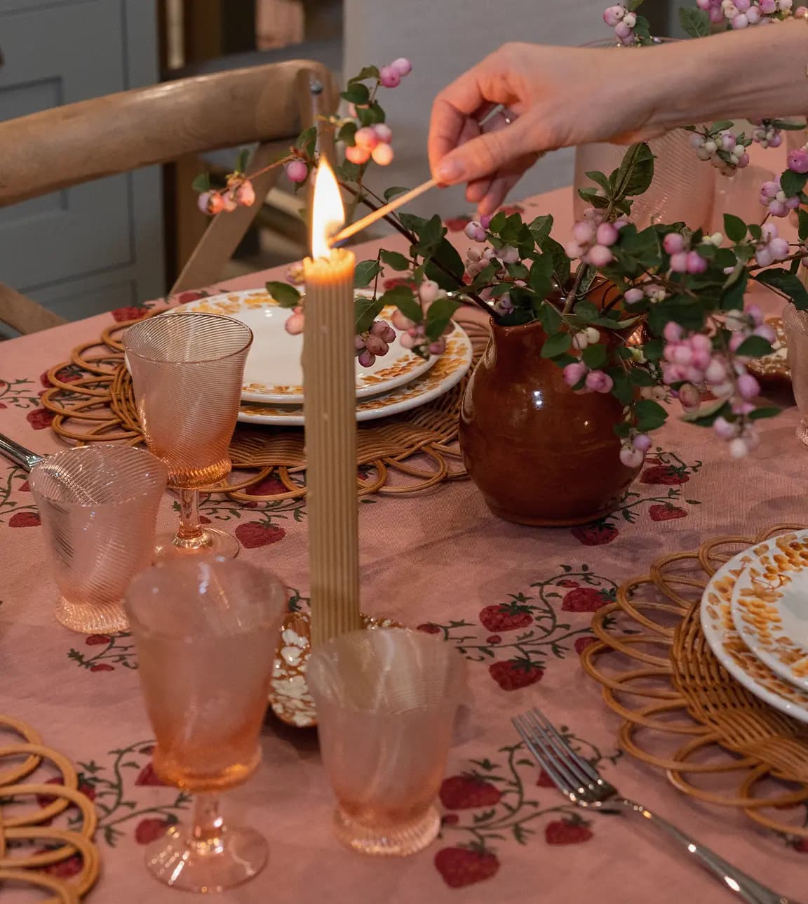 A hand lights on a candle on a cosy autumn tablescape in The Wedding Present Company showroom
