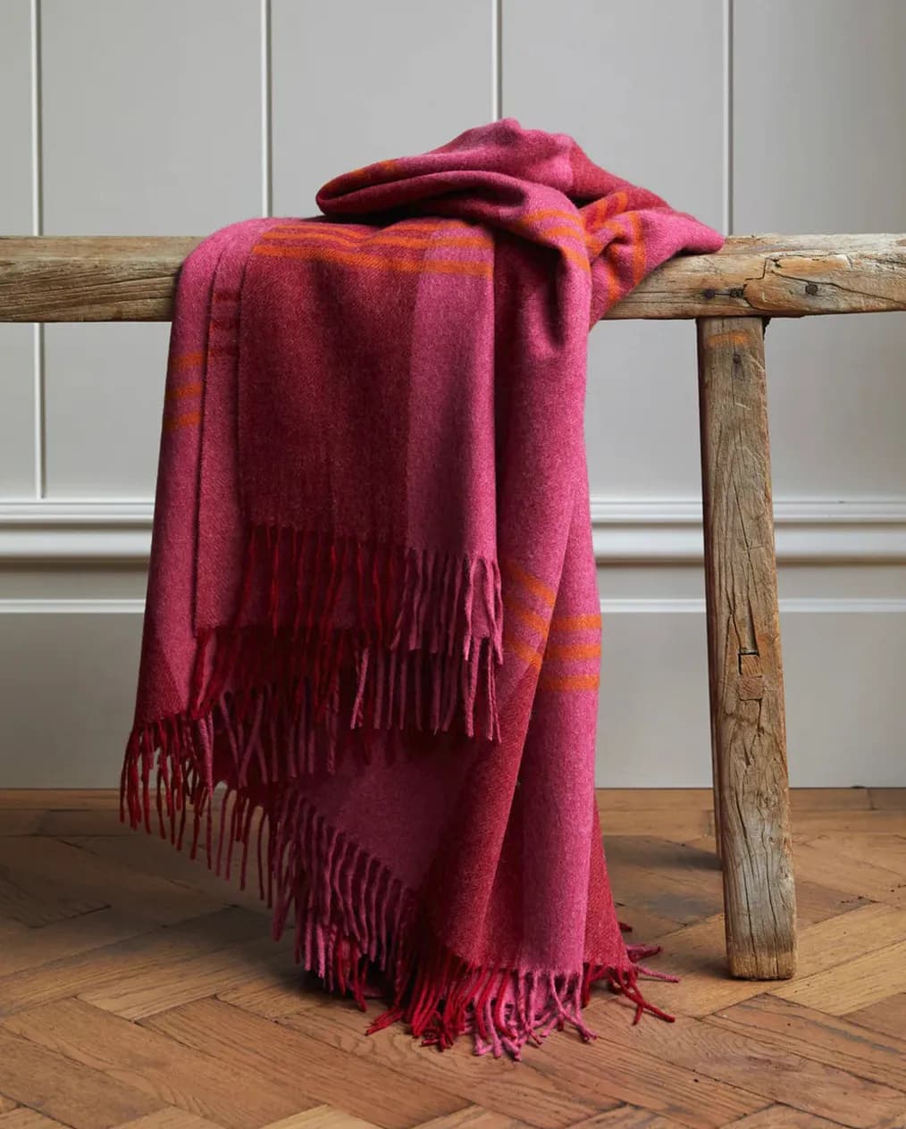 A hot pink throw is thrown over a wooden bench
