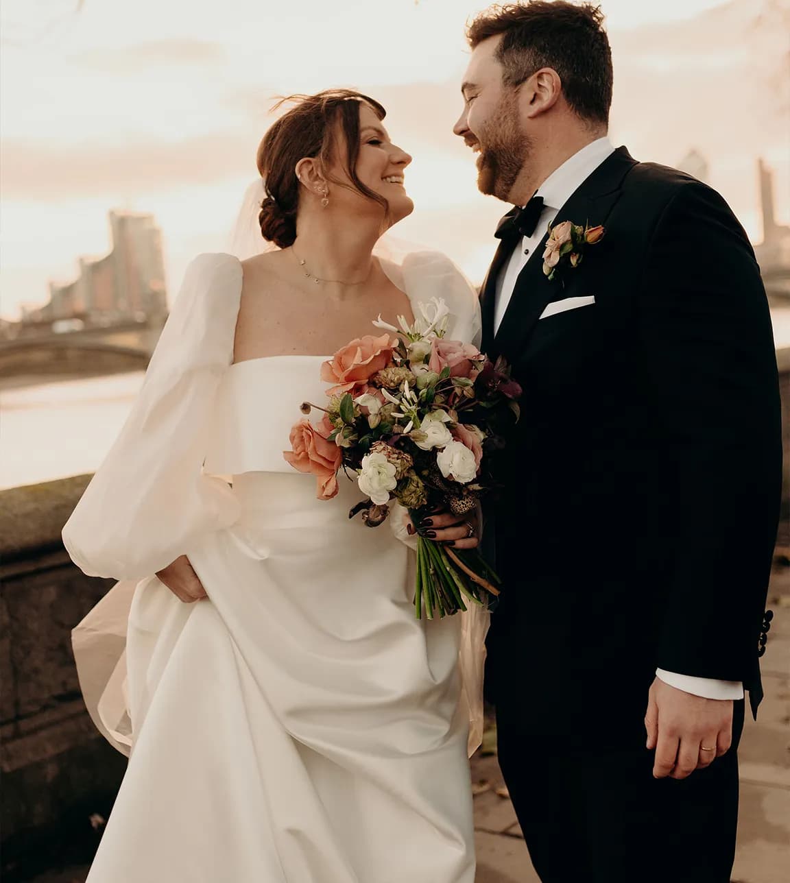 Bride and groom look at each other with the London lanscape behind 