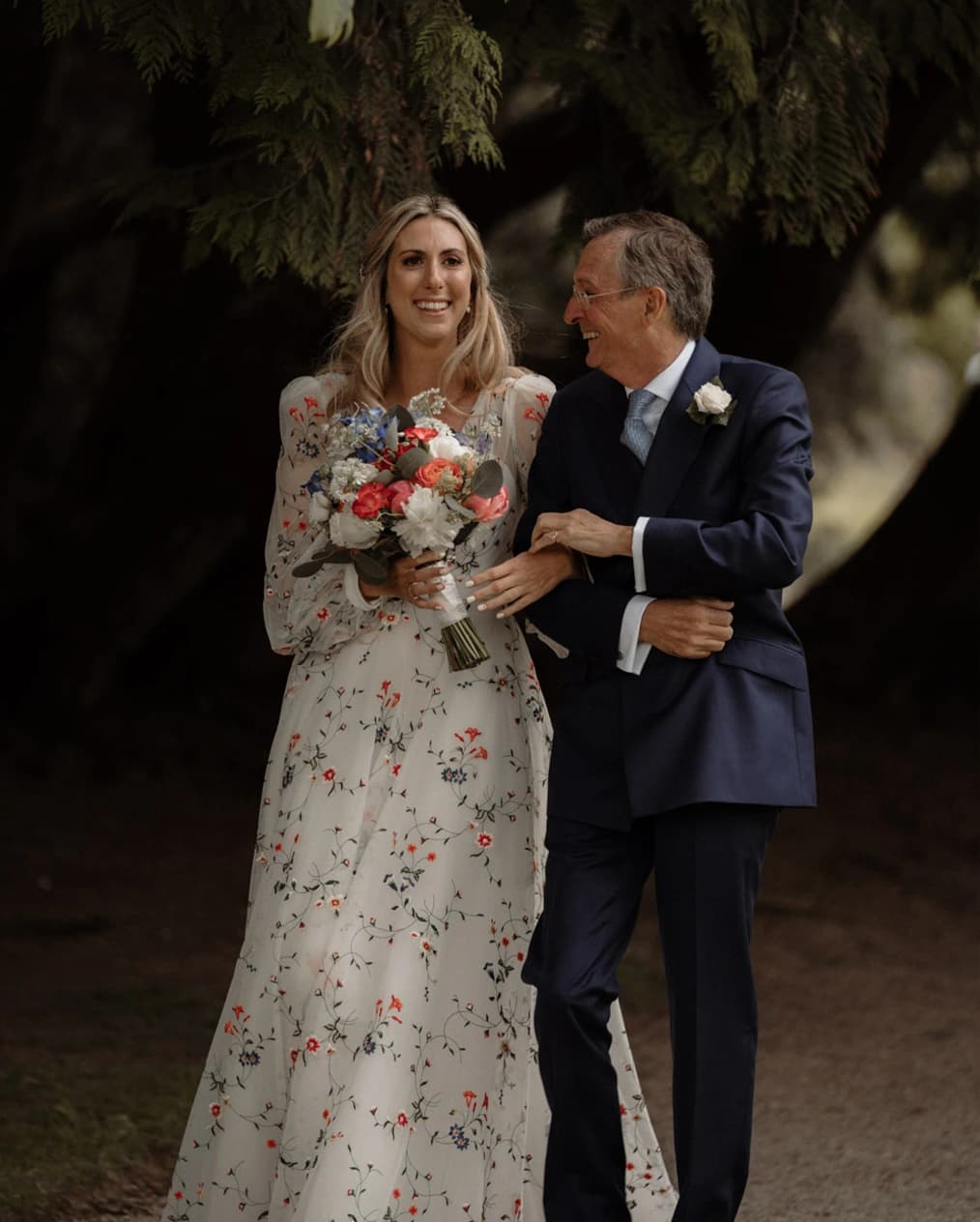 Bride and her father walking down the aisle with her holding a colourful bouquet