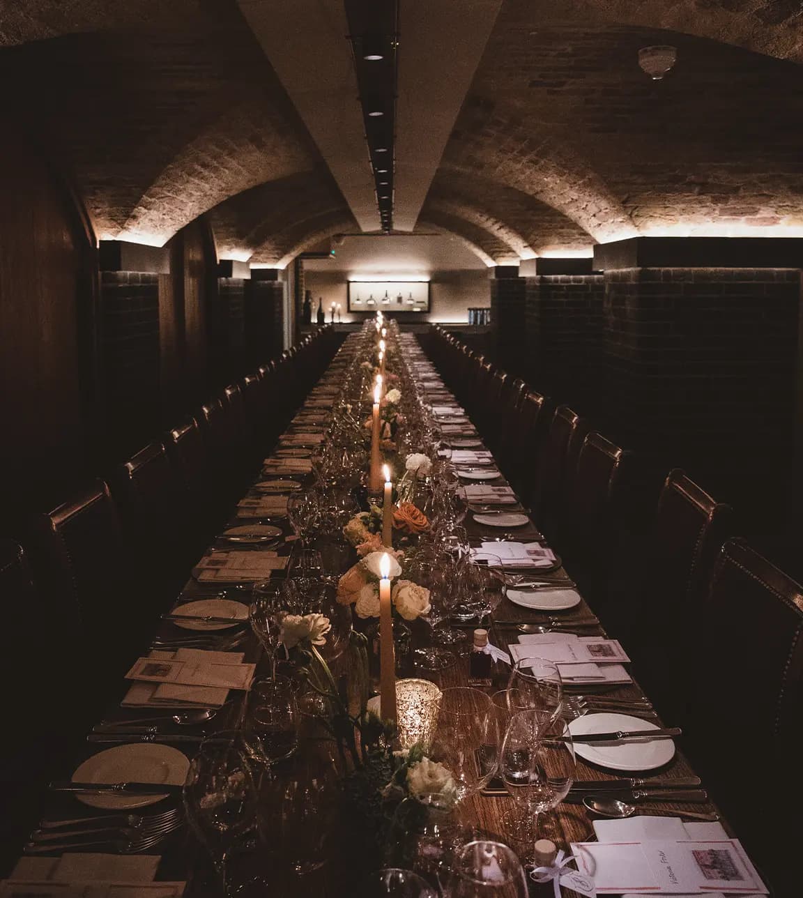 Wine cellar reception venue featuring a long table adorned with flowers and candles