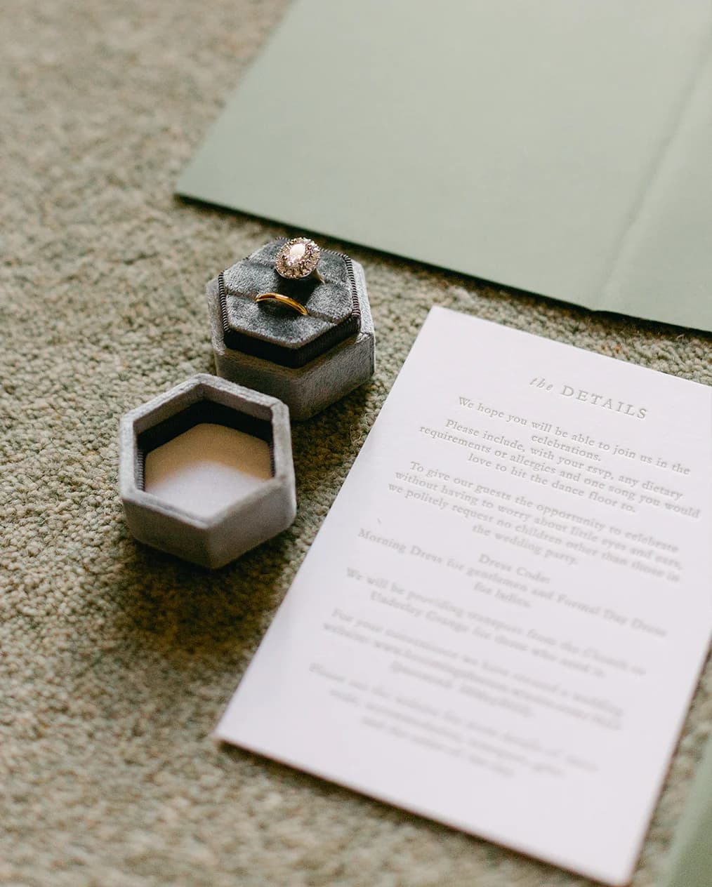 Elegant embossed wedding stationery placed next to engagement ring in abox
