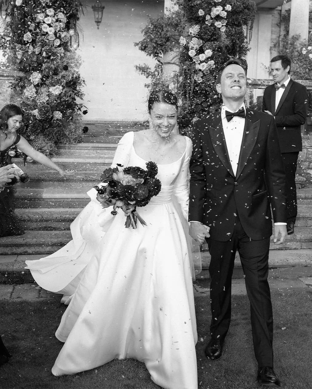 Happy bride and groom walk through the confetti thrown buy the wedding guests