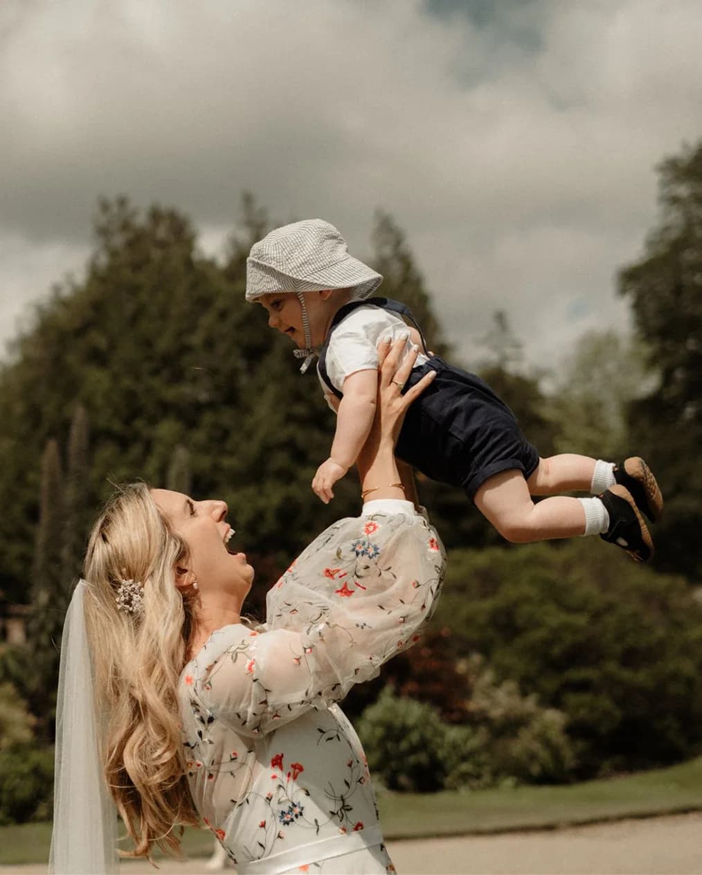Bride lifting her baby son, the page boy, above her head