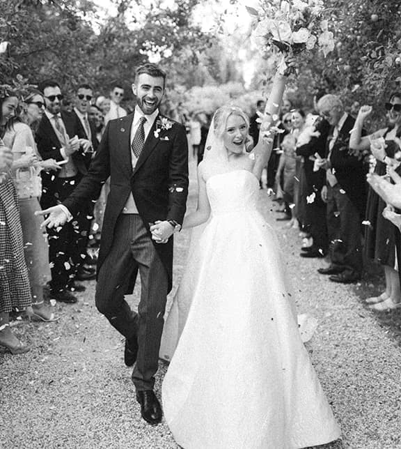 Bride and groom celebrate their English country garden wedding in Hampshire with confetti