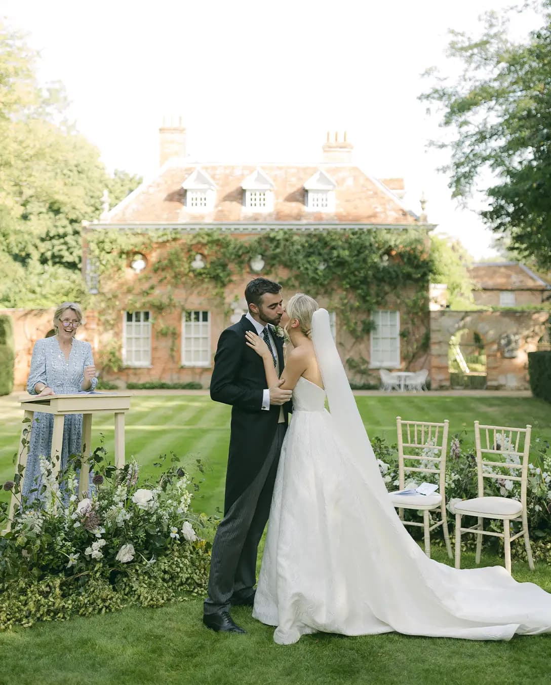 Bride, groom, and celebrant at outdoor wedding ceremony by Georgian house in Hampshire