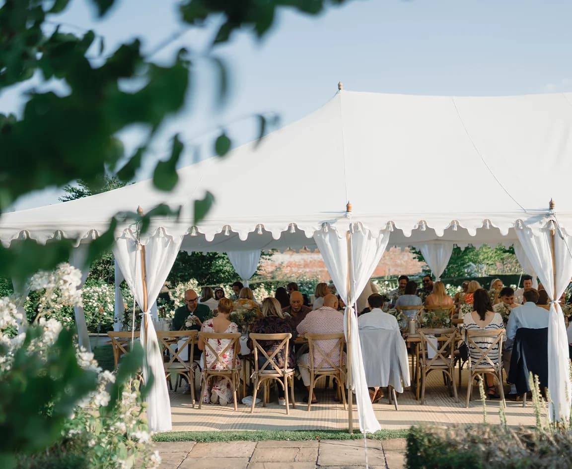 Wedding guests enjoy reception inside a beautiful wedding marquee