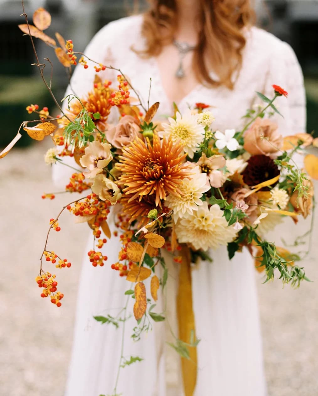 A woman holds a yellow and orange autumn flower bouquet