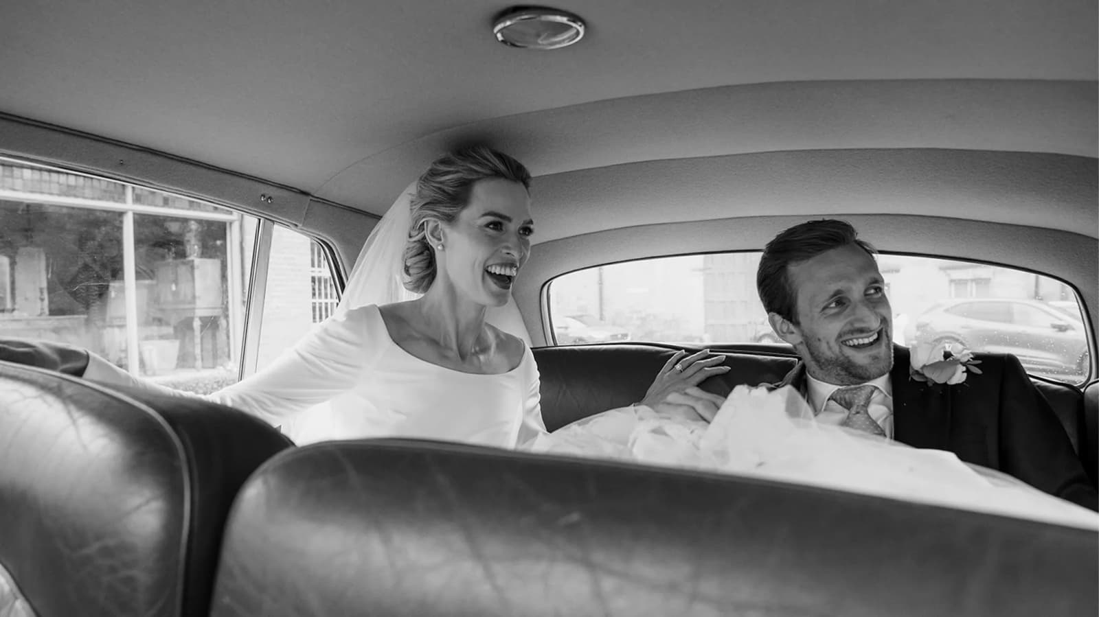 Bride and groom smiling in their wedding car