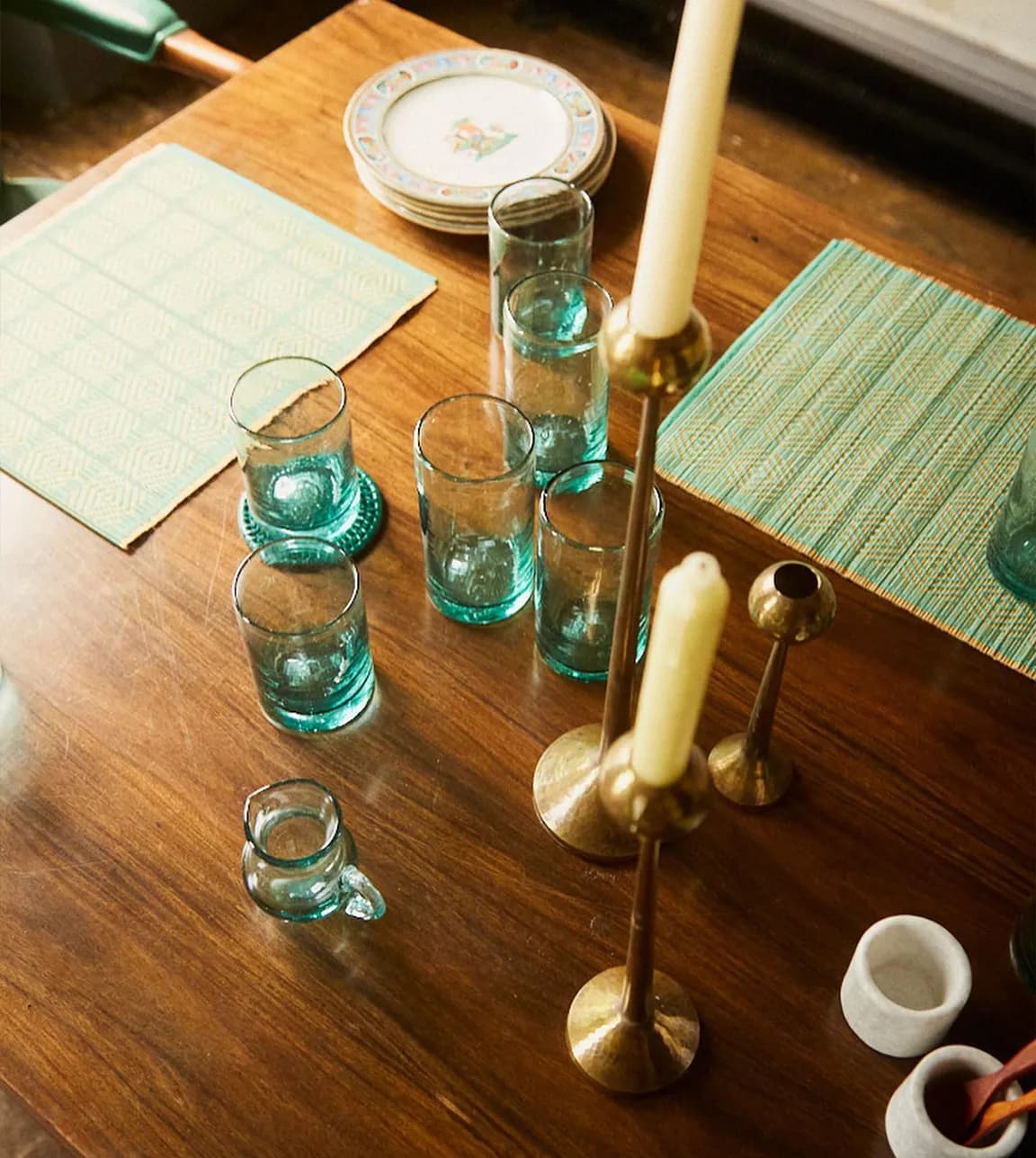 A dining table displays Kalinko recycled glassware and brass candleholders