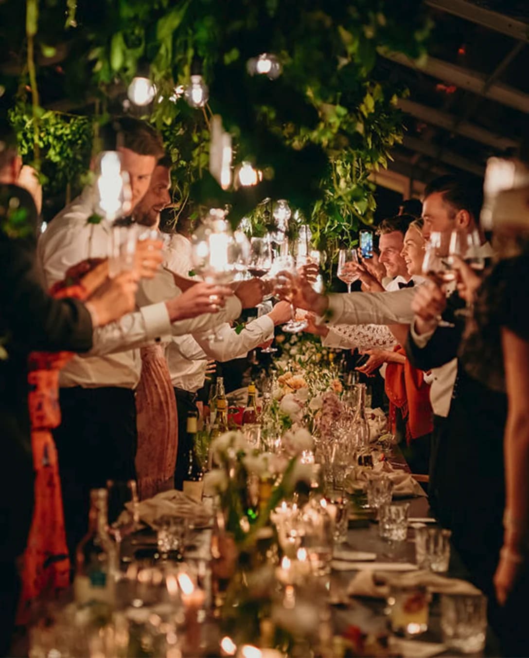 Wedding guests toast with drinks during wedding dinner inside a marquee 