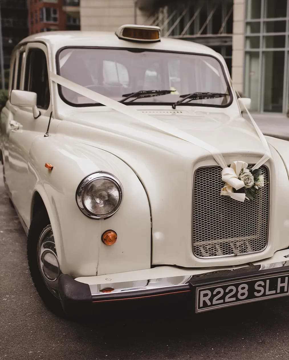 Cream white London cab taxi decorated for a wedding