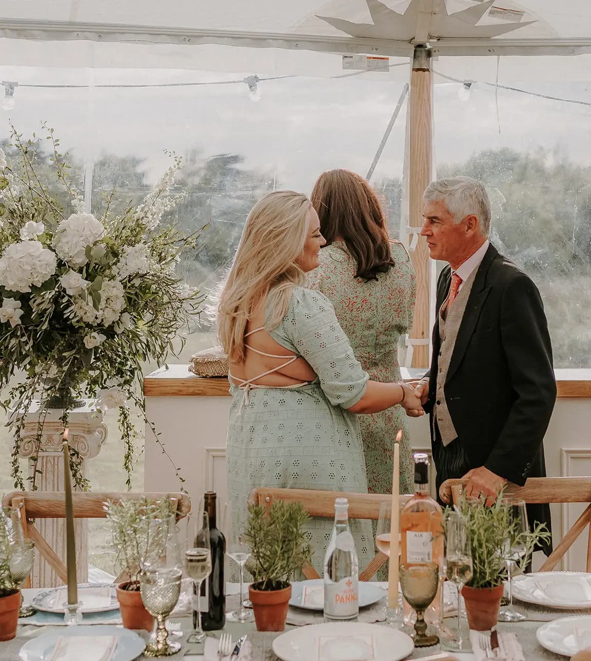 Wedding guests shake hands with each other during marquee wedding reception