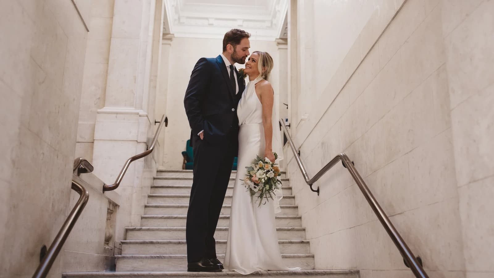 Bride and Groom posing on a grand marble staircase