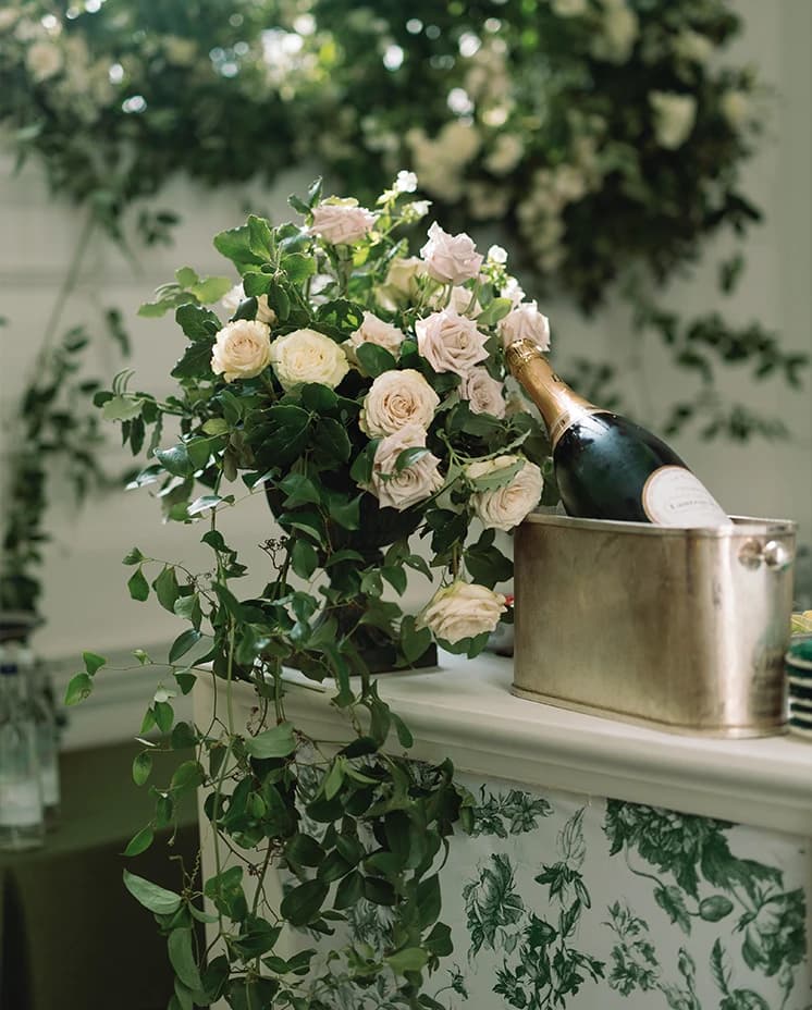 White and green wedding floral decor next to an ice bucket with champagne