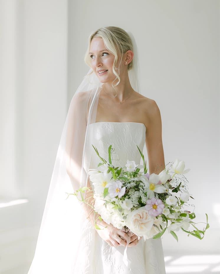 A traditional bride wears delicate Sassi Holford strapless dress and veil.