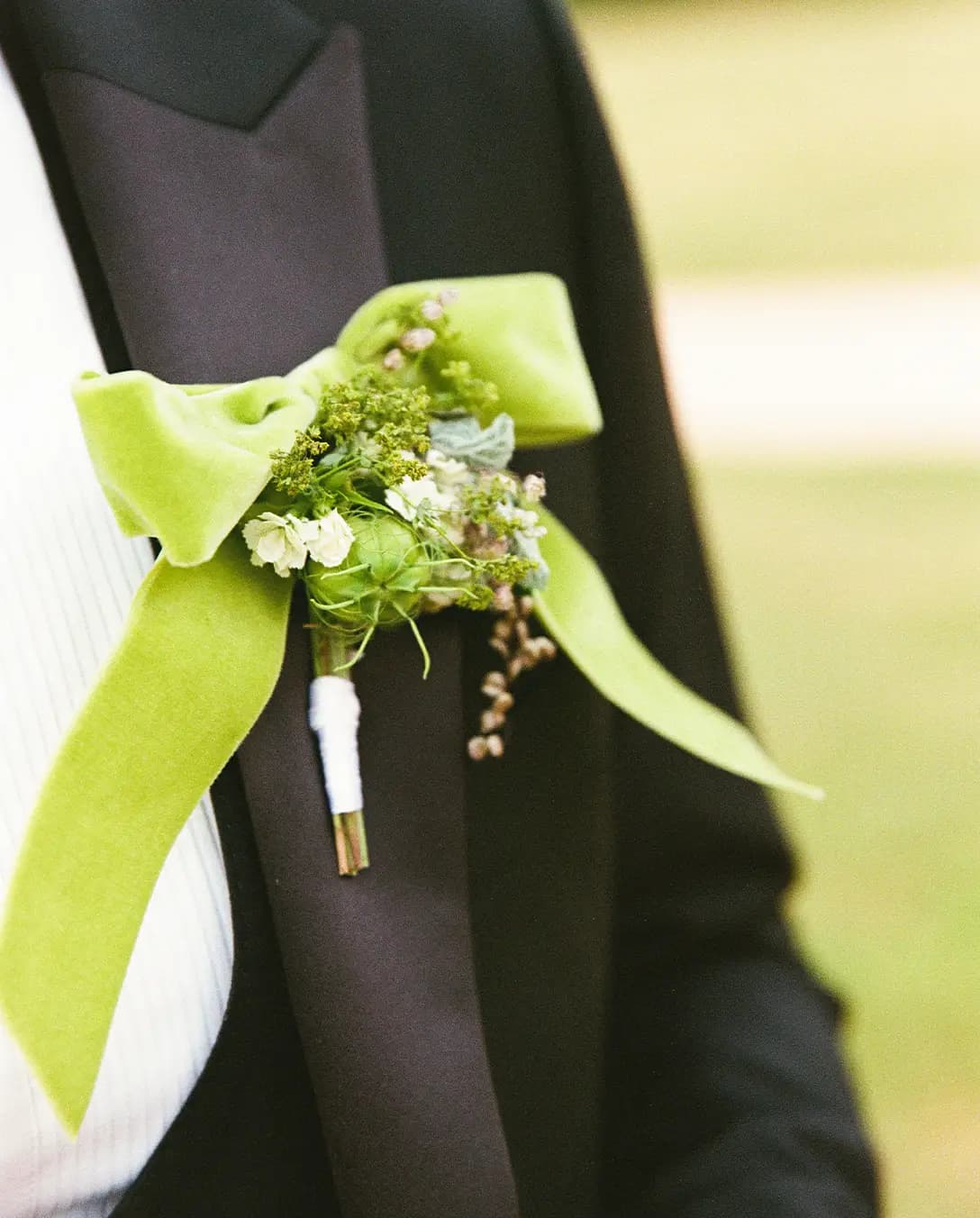 groom's tuxedo lapel decorated with a green bow and delicate flowers