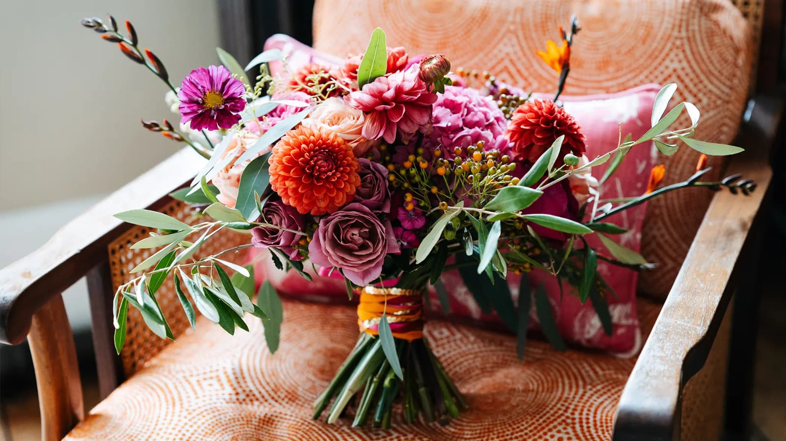 Colourful autumn wedding flower bouquet is placed on upholstered chair