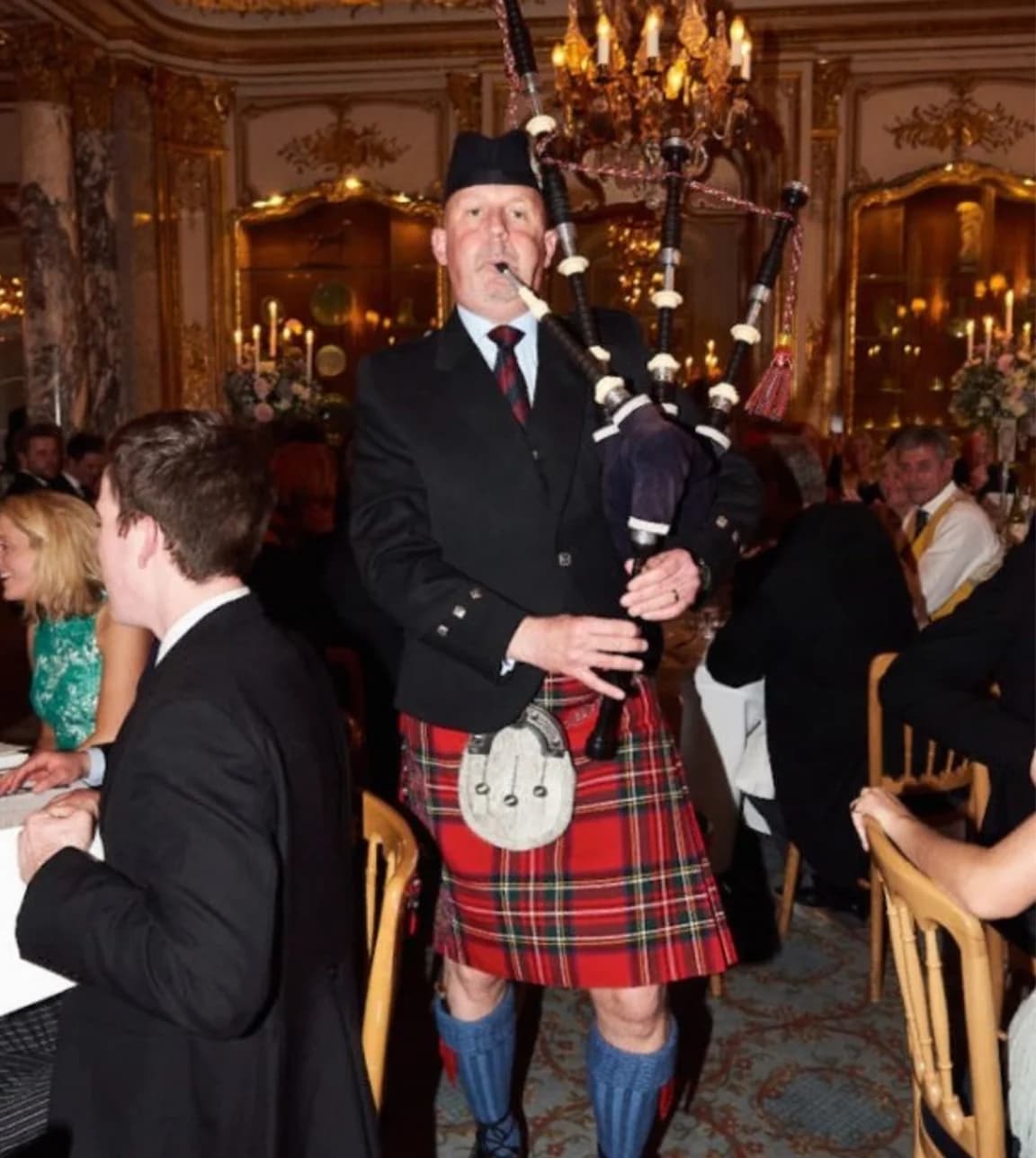 Scottish Piper playing the bagpipes wearing a red kilt and traditional dress