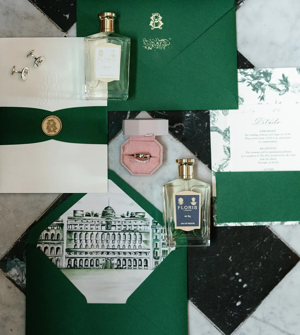 Luxury green wedding invite and stationery arranged next to wedding band and perfume