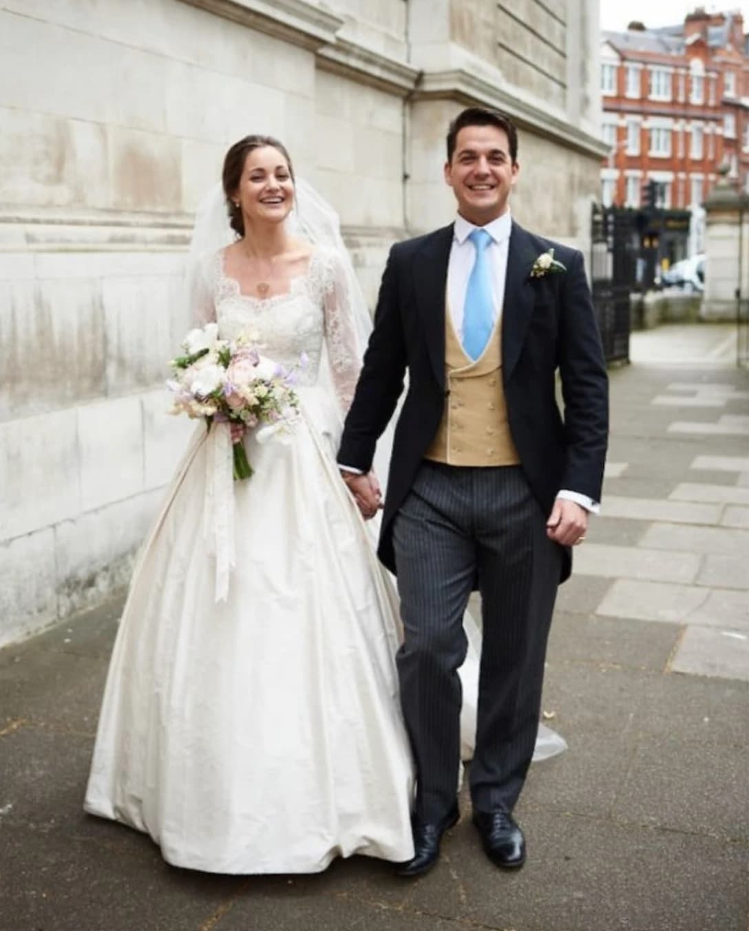 bride and groom walking hand-in-hand and smiling on street at their London Spring wedding