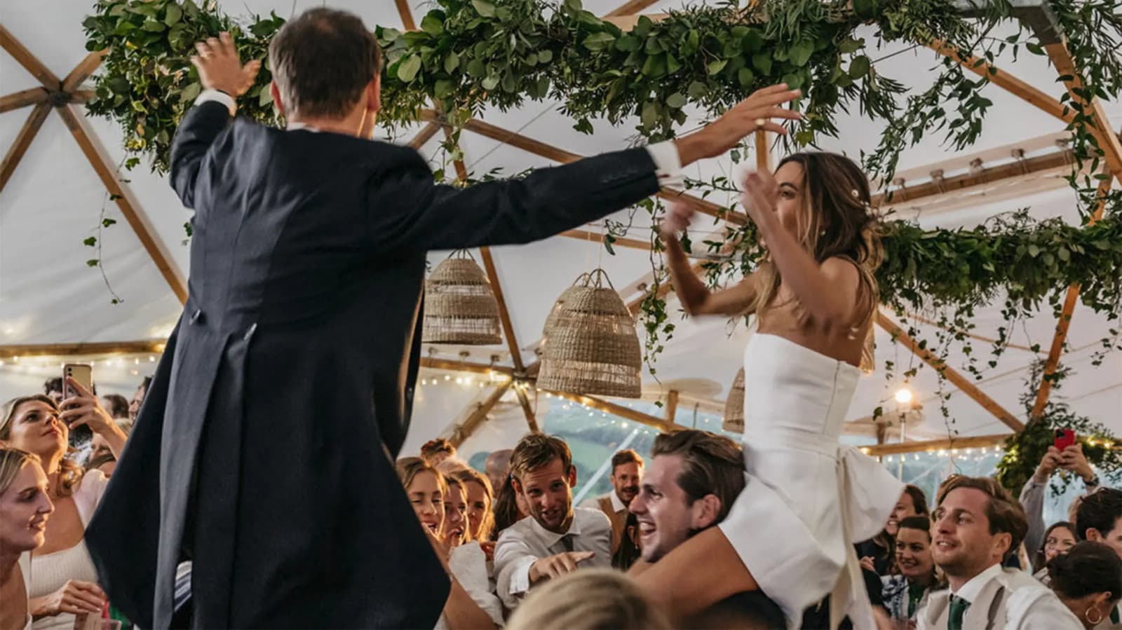 Bride and groom do their first dance on the shoulder of wedding guests.