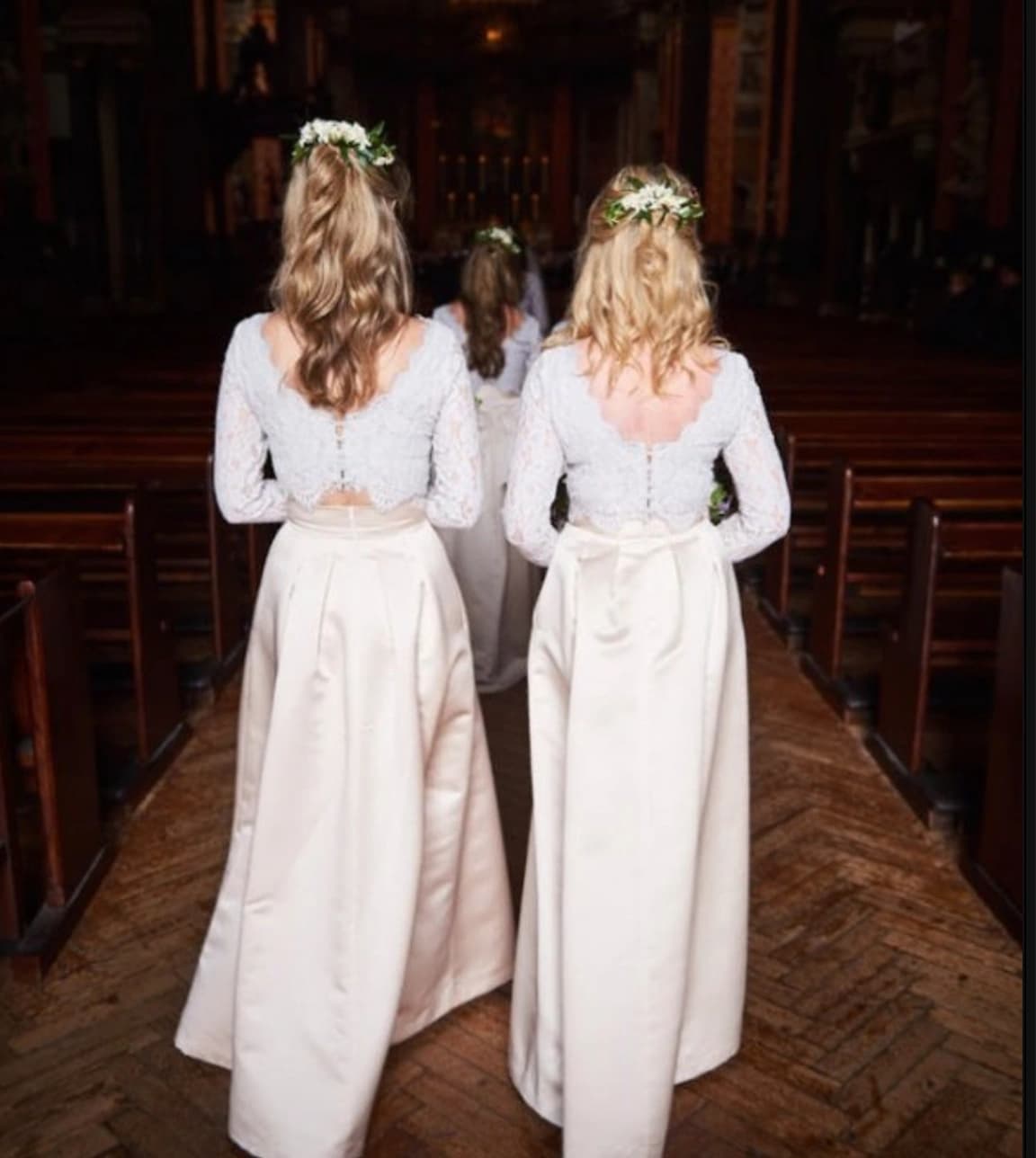 two bridemaids walking down the aisle in matching white dresses and hairstyles