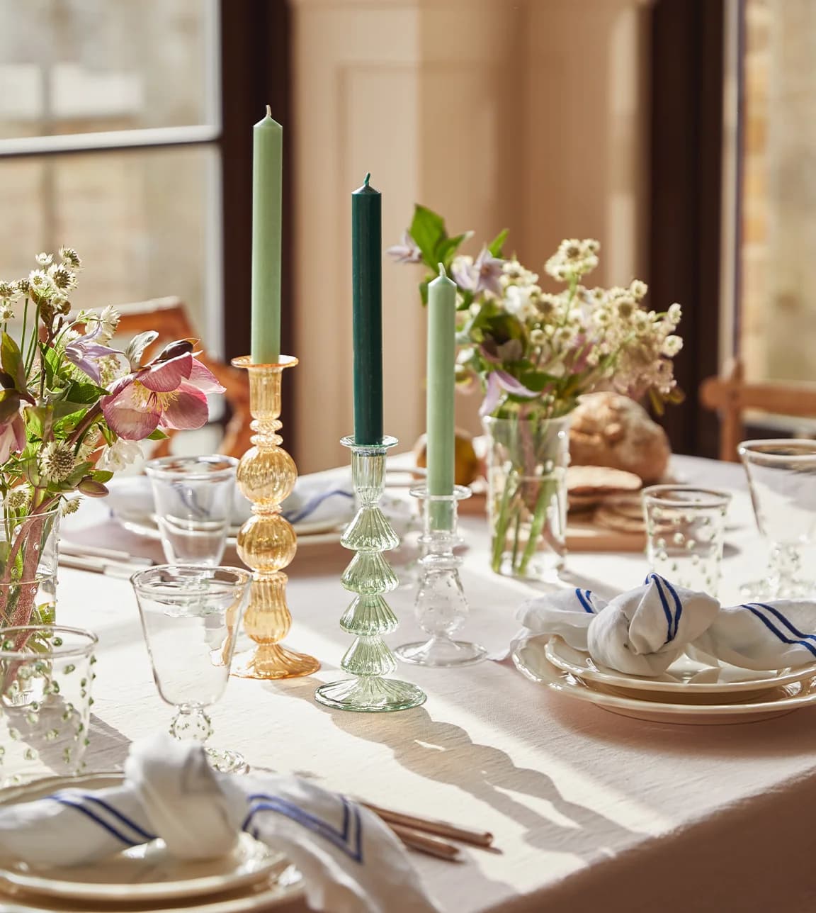 A sunlit dining table set with colourful glassware and homeware from Issy Granger