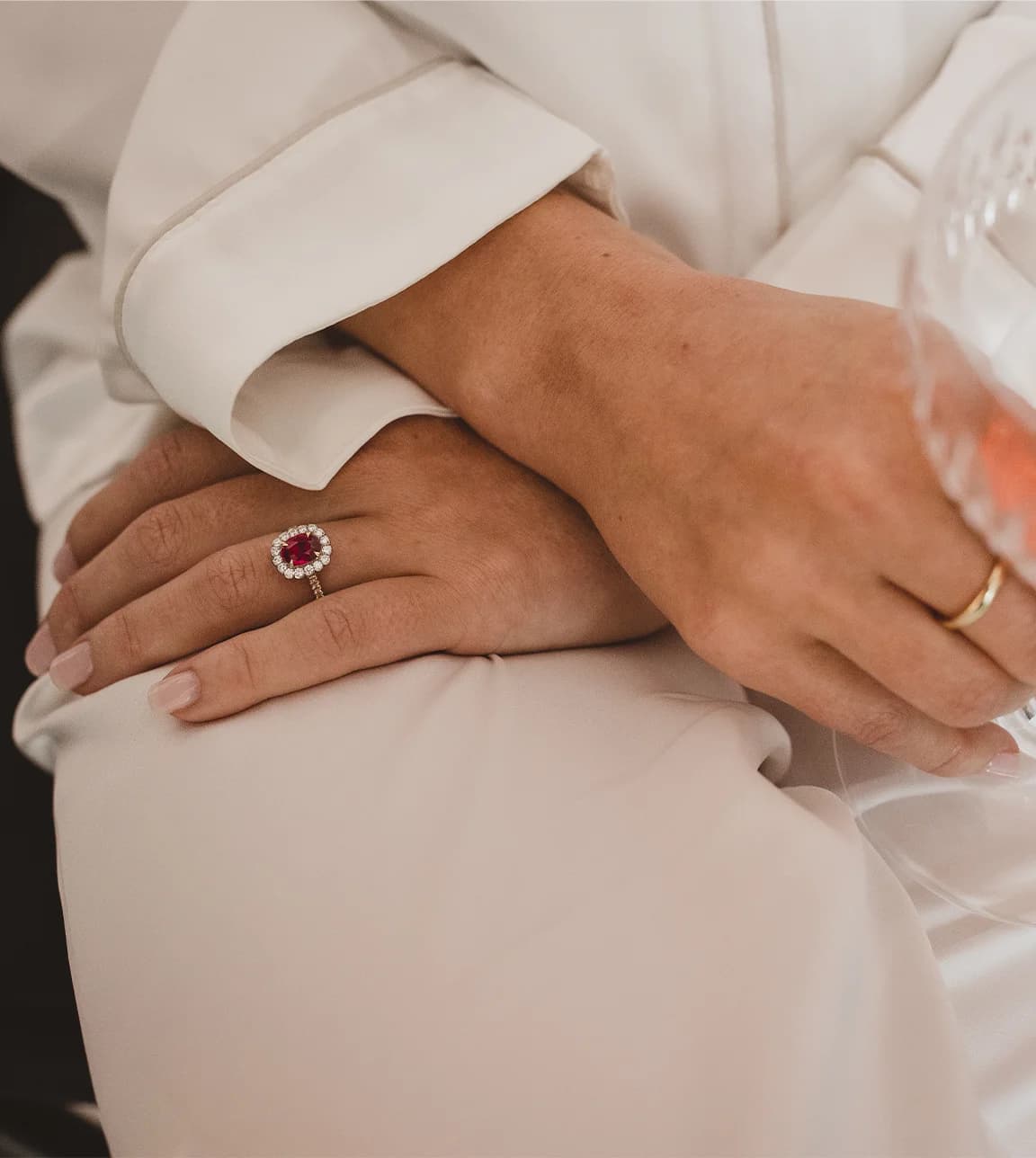 Close-up of bride wearing a ruby engagement ring and holding a glass of champagne