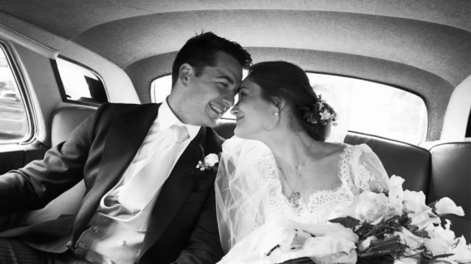 bride and groom smiling in backseat of car
