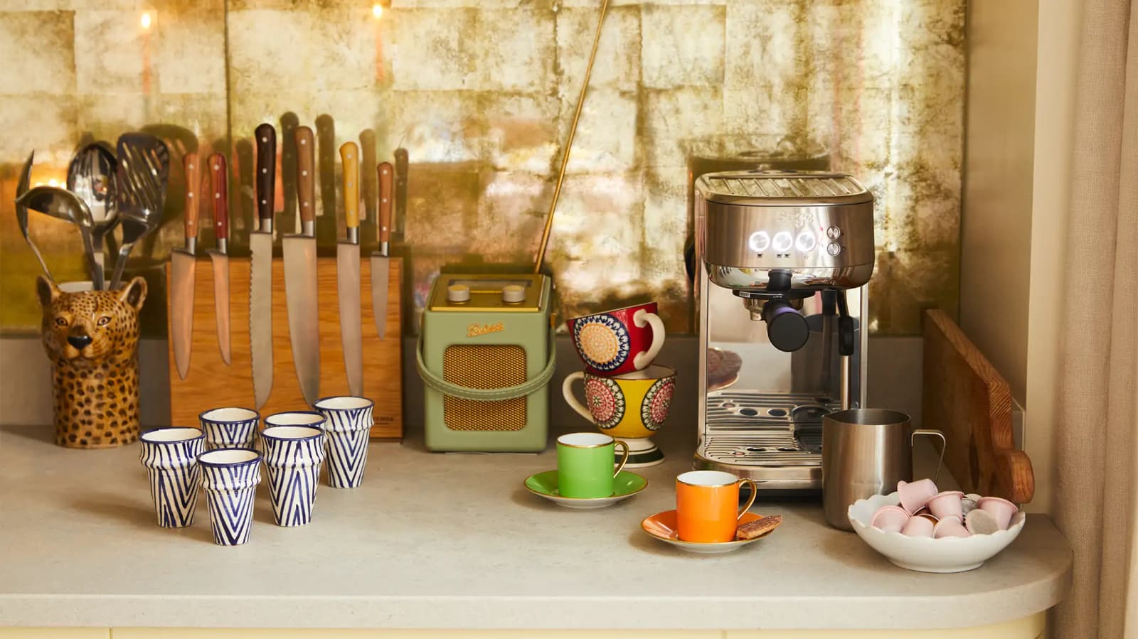 Luxury wedding presents Sage coffee machine and handpainted ceramics coffee cup are on a kitchen counter.