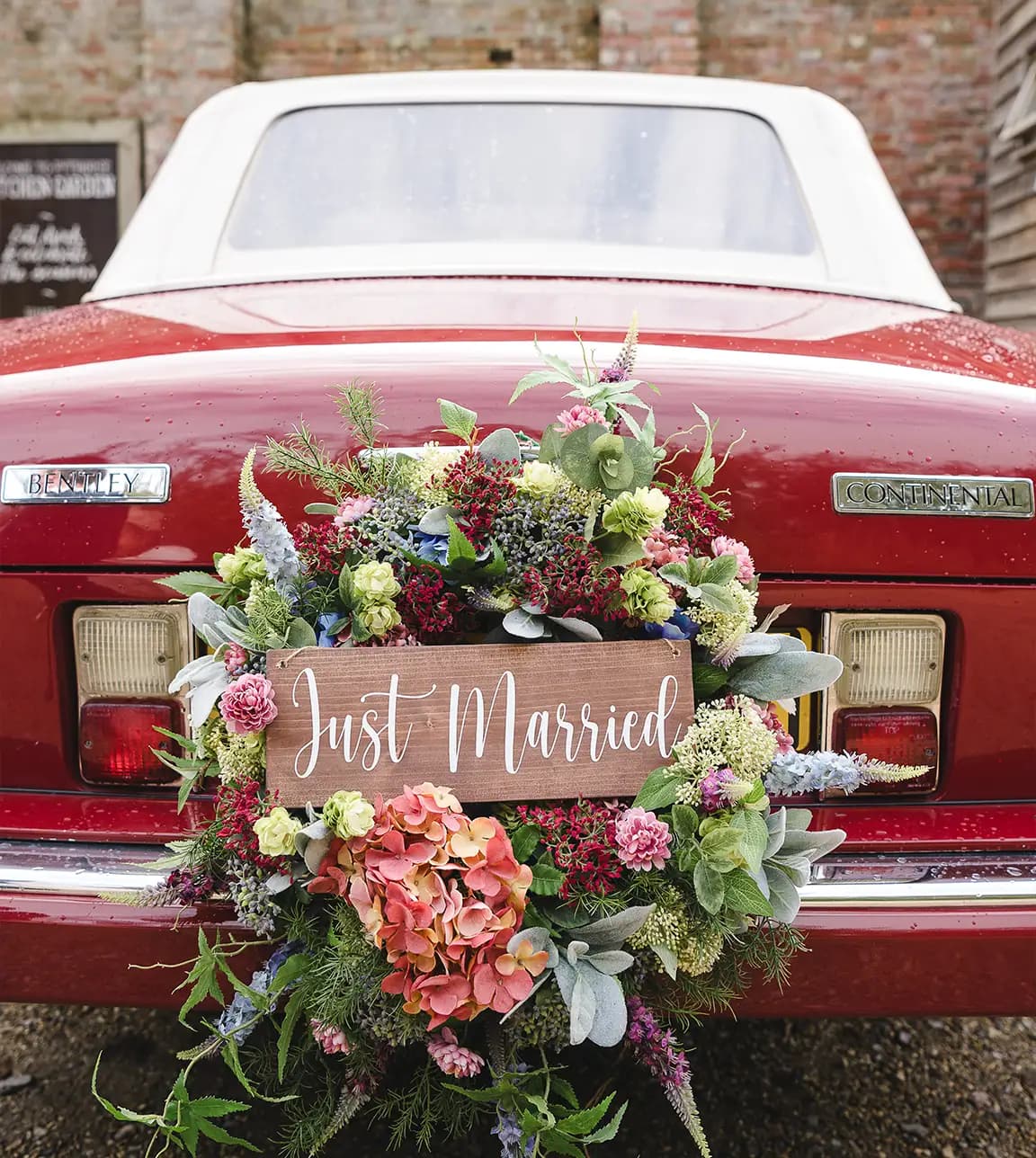 A red vintage wedding car with autumn wedding flower wreath