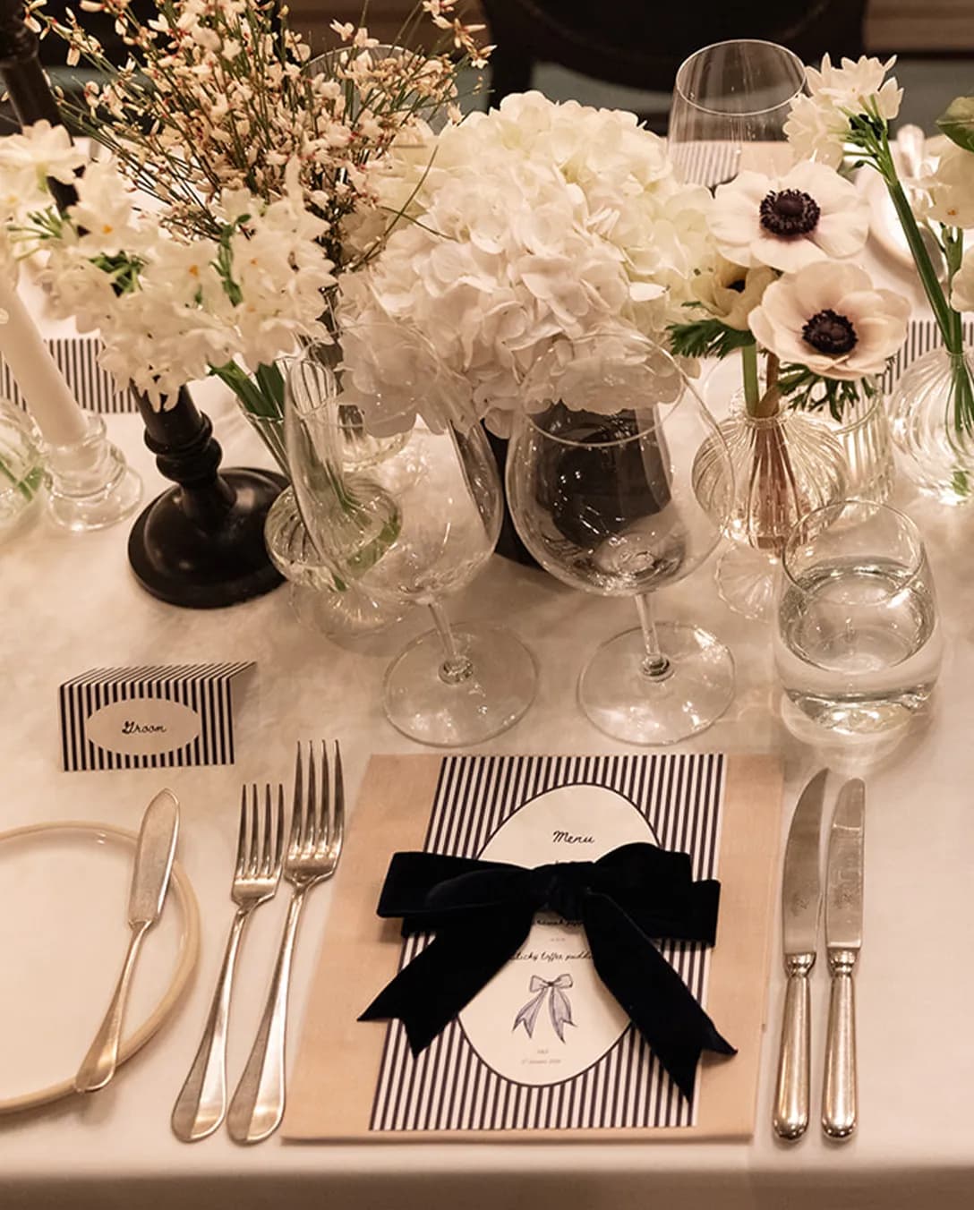 Luxury drama table setting with white flowers and black velvet bow and candles placed on the table