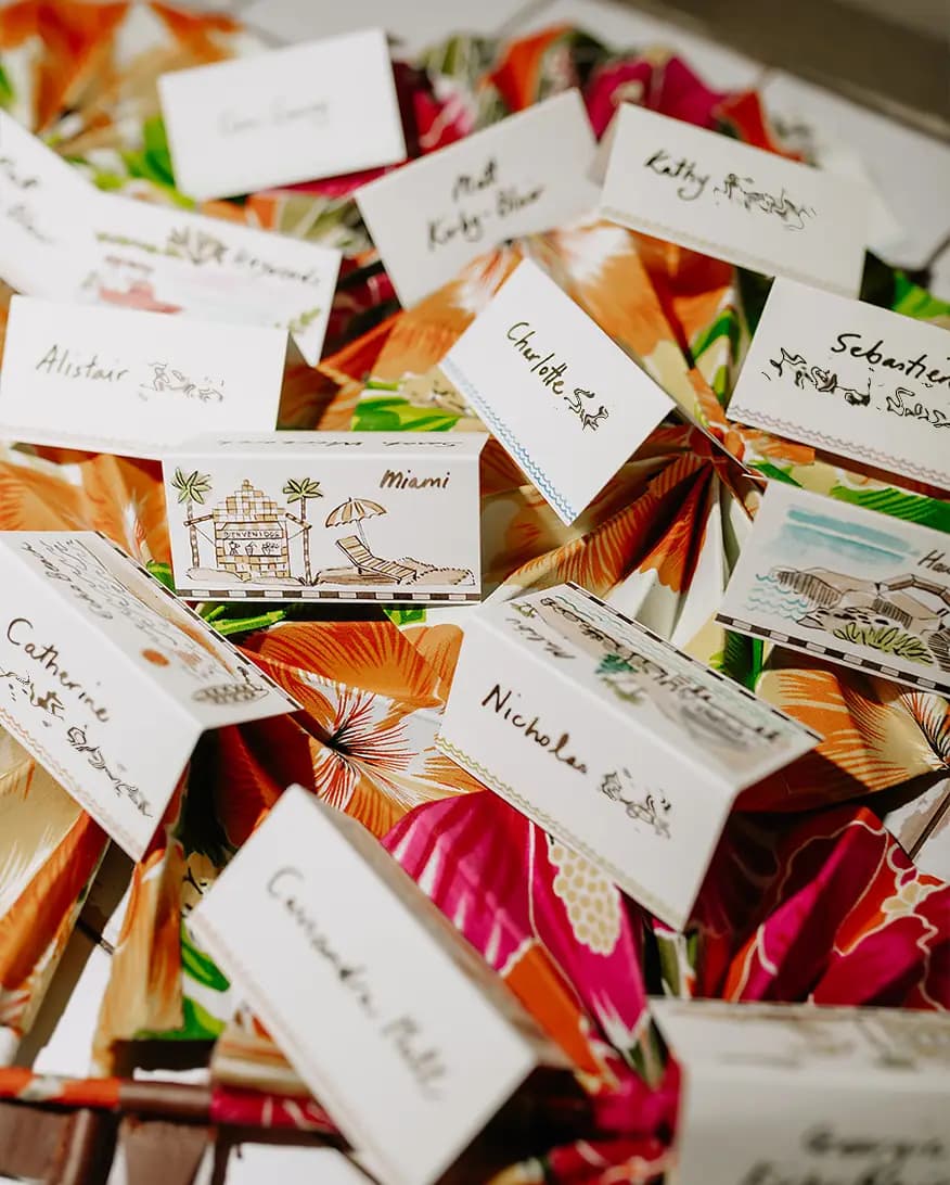 Colourful Caribbean-themed wedding place cards on a floral tablecloth