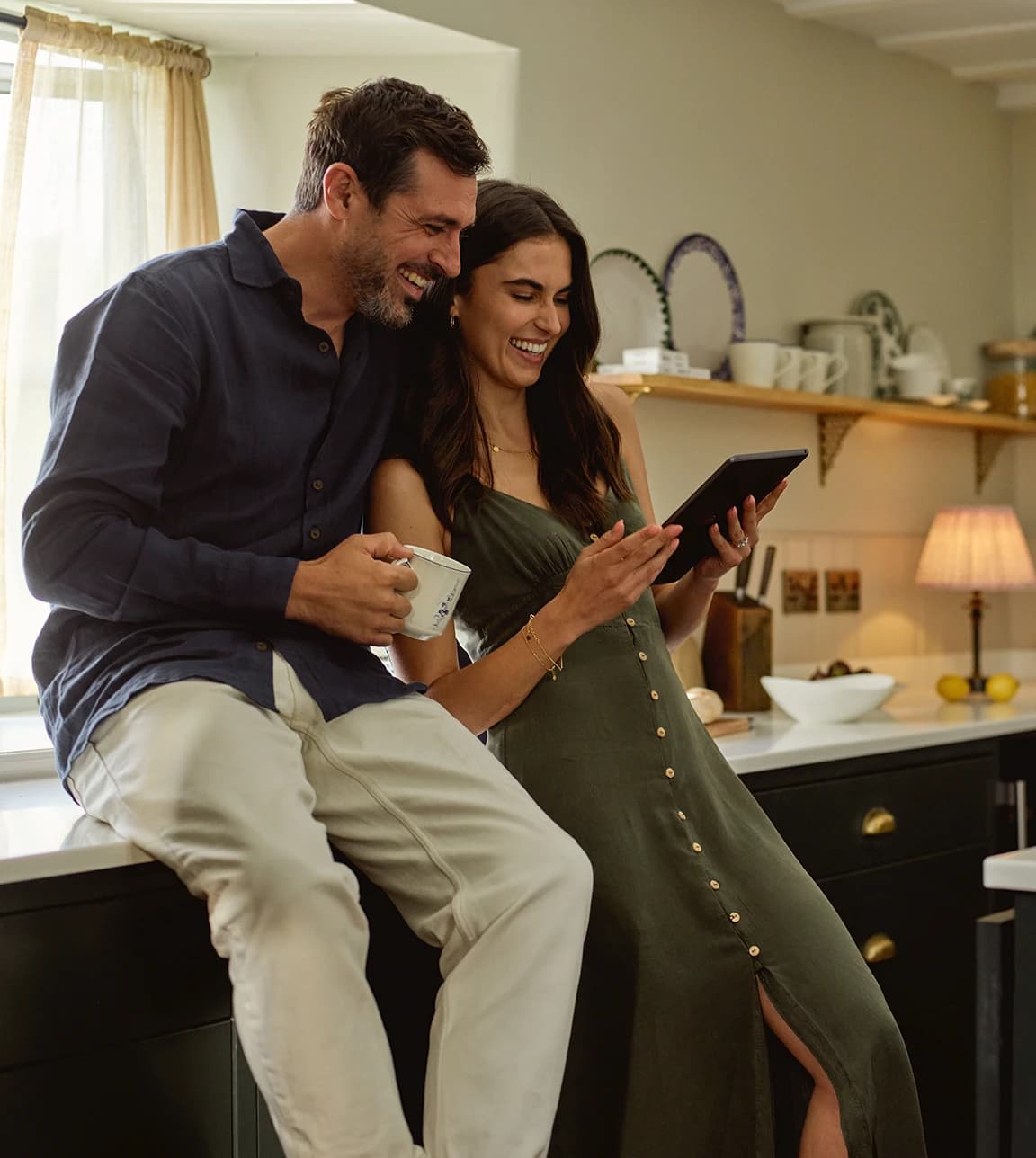 Happy groom and bride create their luxury wedding registry on the iPad in their kitchen